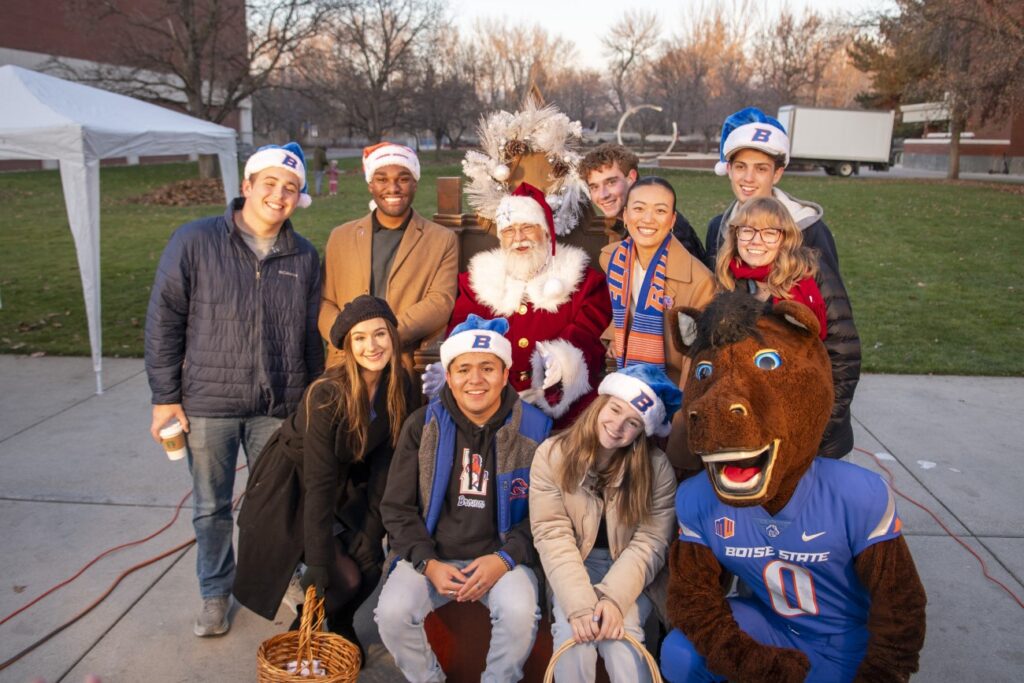 Group of students posing with Santa at tree lighting event.