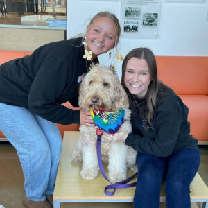 Peer Health Educators Abby Brinkley and Sydney Moir pose with Kirby a therapy dog.