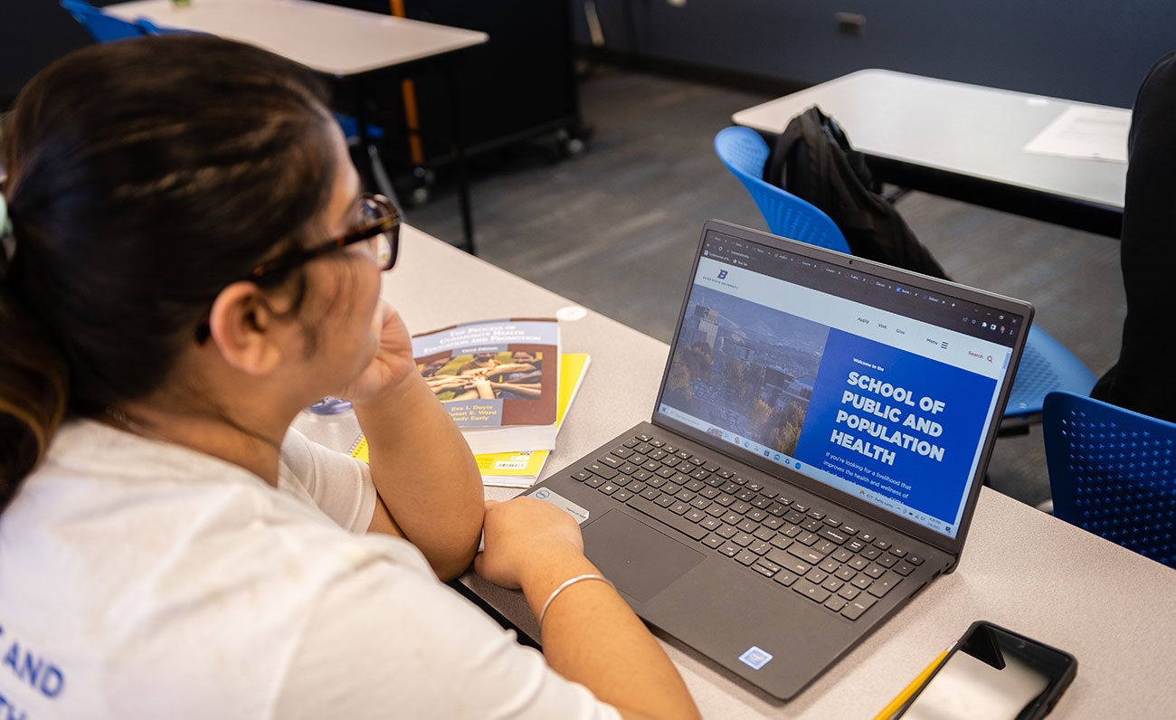 Student looks at laptop with the School of Public and Population Health website on screen