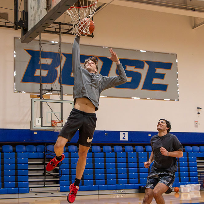Boise State K-12 PE student jumps to make slam dunk in Instructional Basketball class in BroncoGym