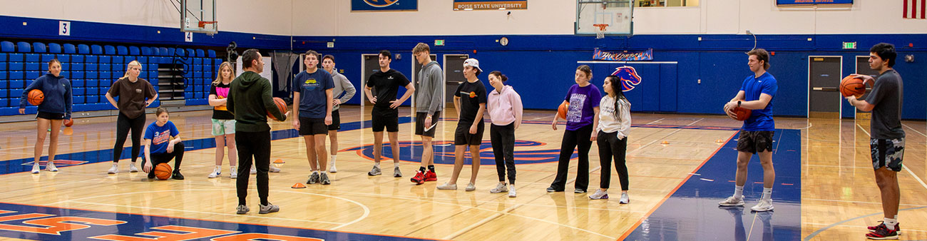 Faculty Tyler Johnson gathers his students around him in Instructional Basketball class in BroncoGym