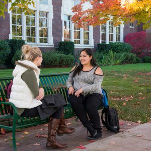 Two students sit on a bench on Boise State University's campus