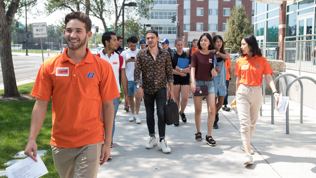 orientation leader walking with a group of students on campus