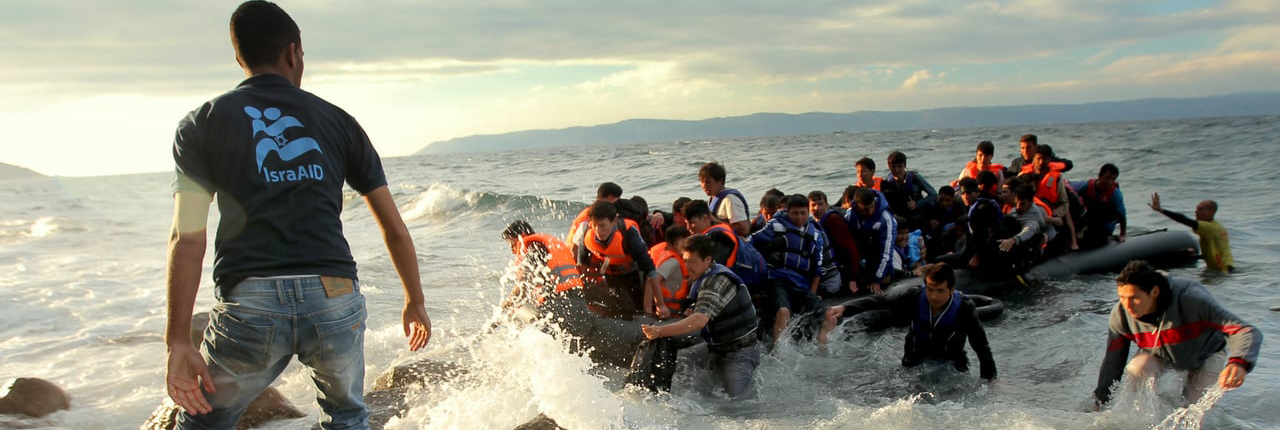 refugees arriving by boat on a beach