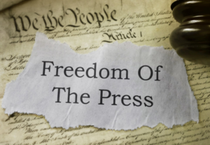The words: freedom of the press on a scrap of paper atop the US constitution.