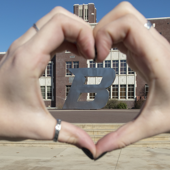 A person making a heart with there hands with the B on the other side