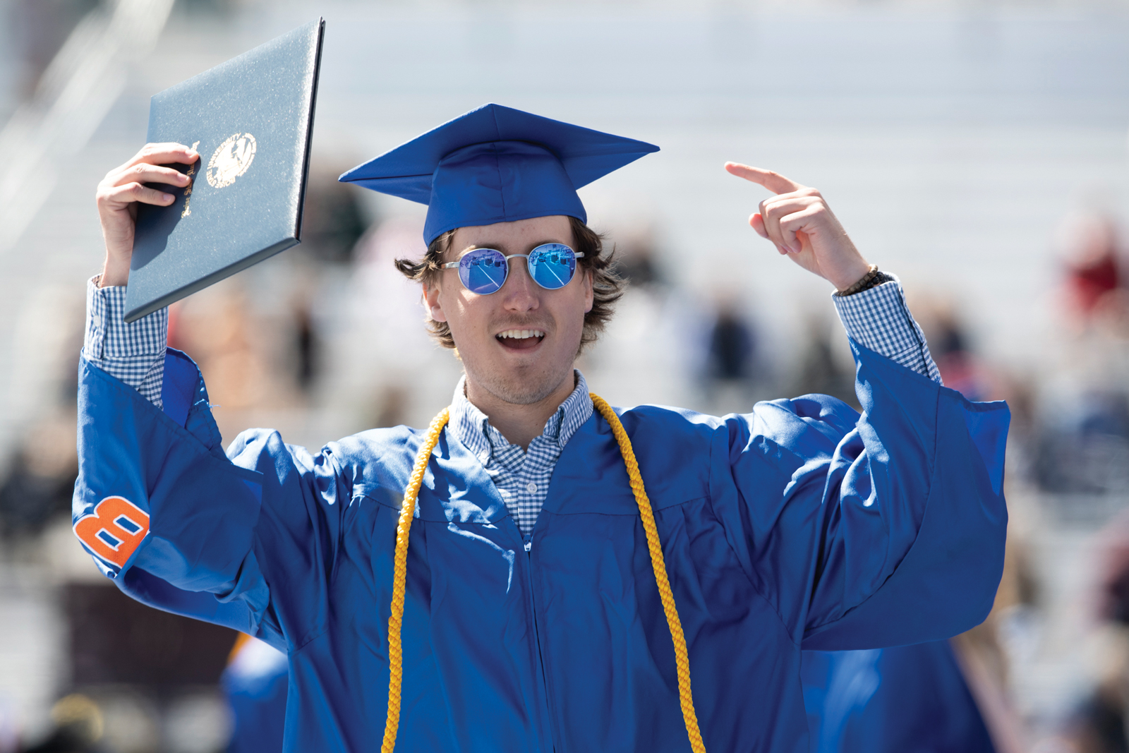 Boise State graduate with a diploma and sunglasses on The Blue