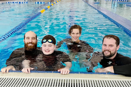 Travis Lundin (left) and Jamie Jones (back) work with neurodiverse student Ethan (second from the left) in developing swim and water safety skills. Lundin first experienced the program as a Service-Learning student when he enrolled in adapted physical education.