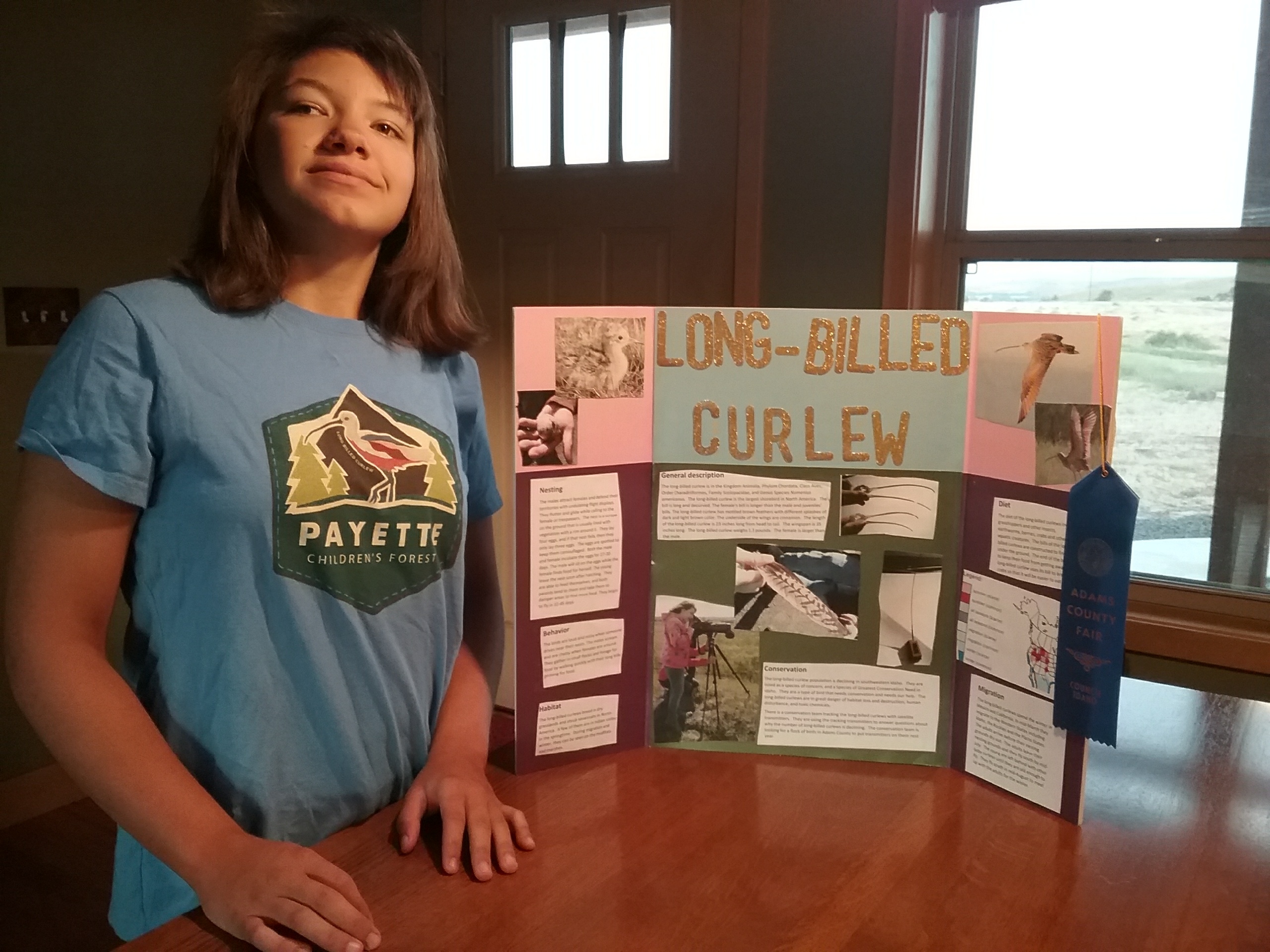 Ruth proudly stands next to her poster with long-billed curlew photos and information