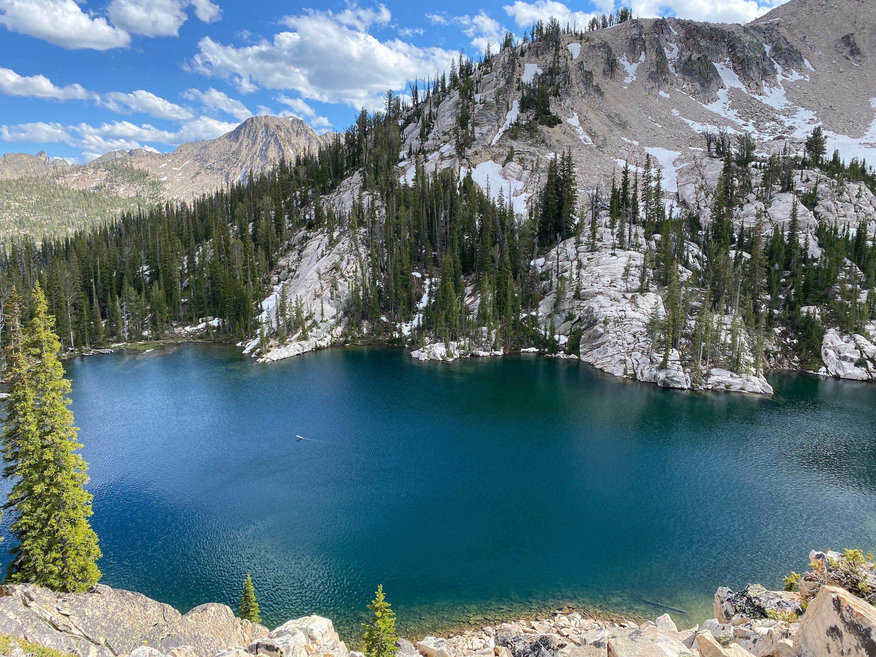a beautiful mountain lake surrounded by spruce forest and high alpine scree and talus slopes