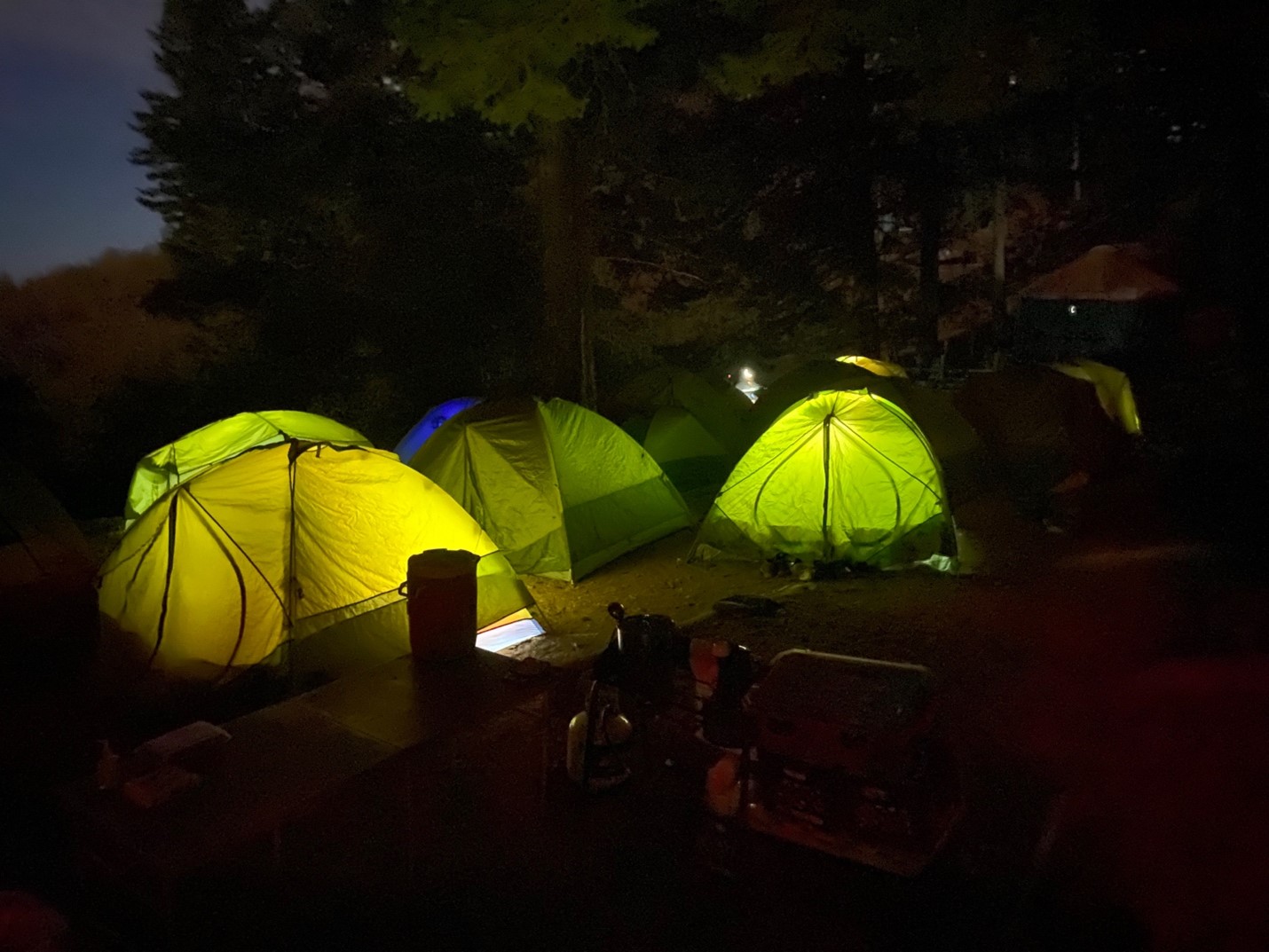 The camping pad at Lucky Peak after dark is crowded with tents. The light of flashlights inside each tent gives off a cheery glow