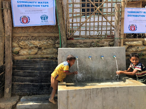 Two children drinking from a fountain in a Rohingya camp