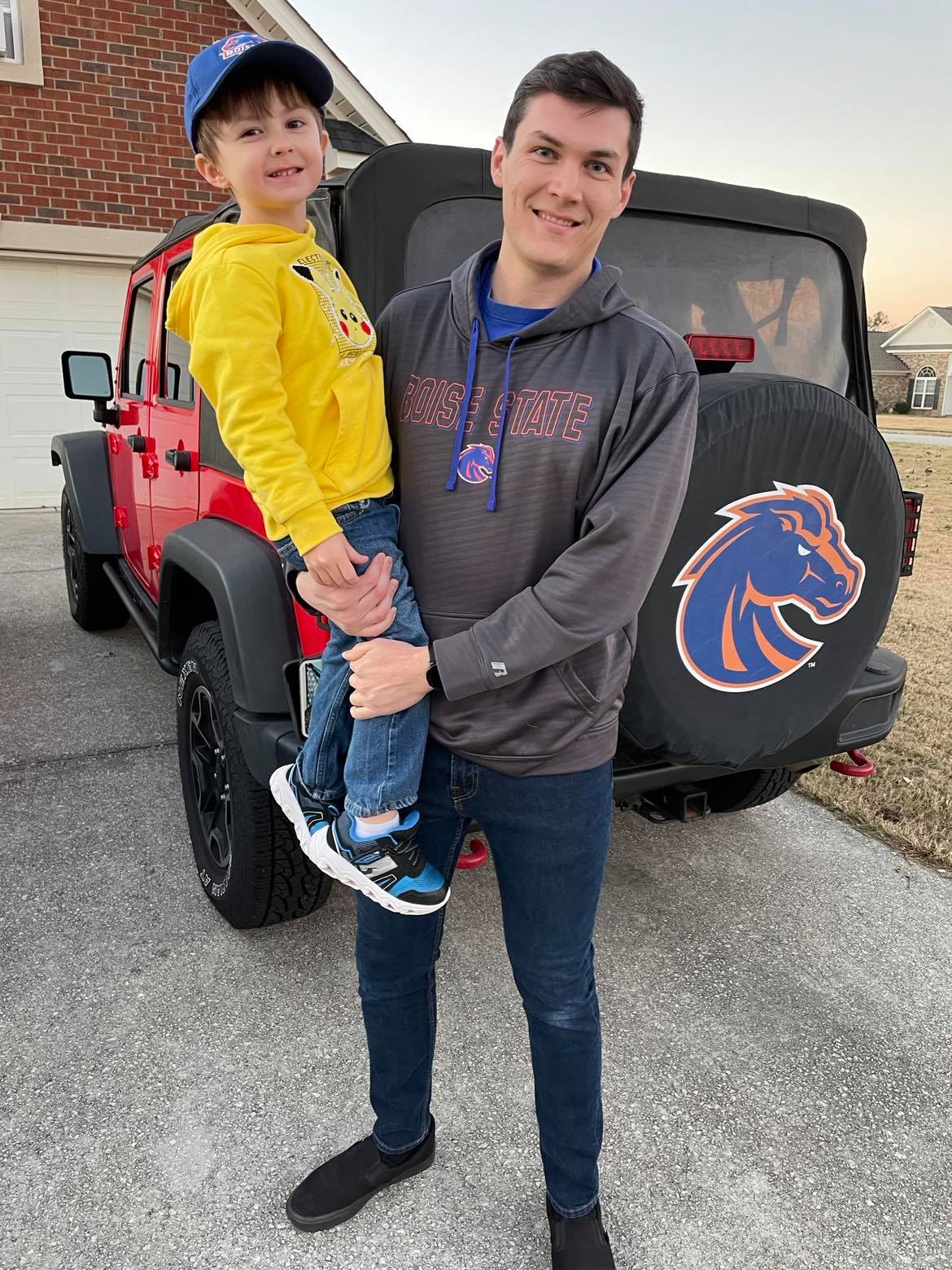 Austin Richardson poses with son in front of a house.