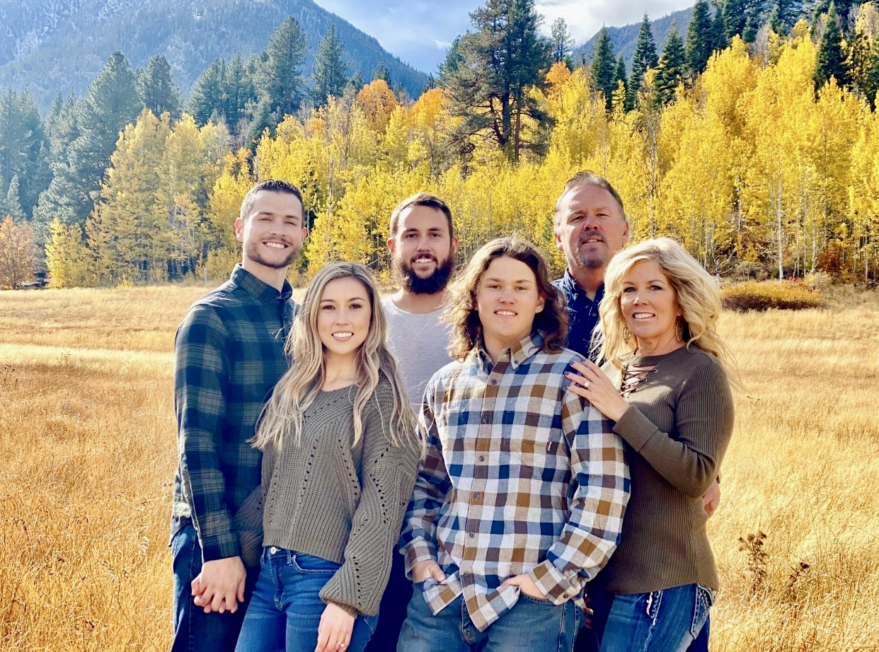 Jessika Wass poses with her family with fall foliage in the background.