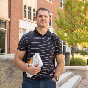 Mason Hampton stands in a courtyard, holding an accounting textbook.
