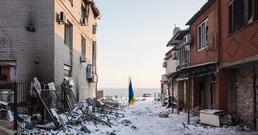 Ukrainian flag stands between two destroyed buildings.
