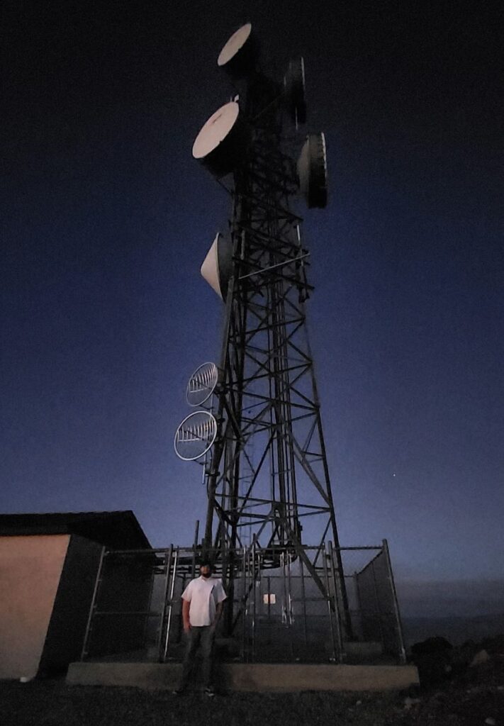 Cameron White standing in front of a radio tower at night