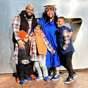 Tino Taufaele with her family, standing in front of the metal Boise State B