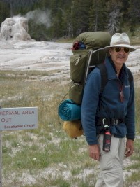 Paul Michaels wearing a pack and outdoor gear, standing near a thermal area