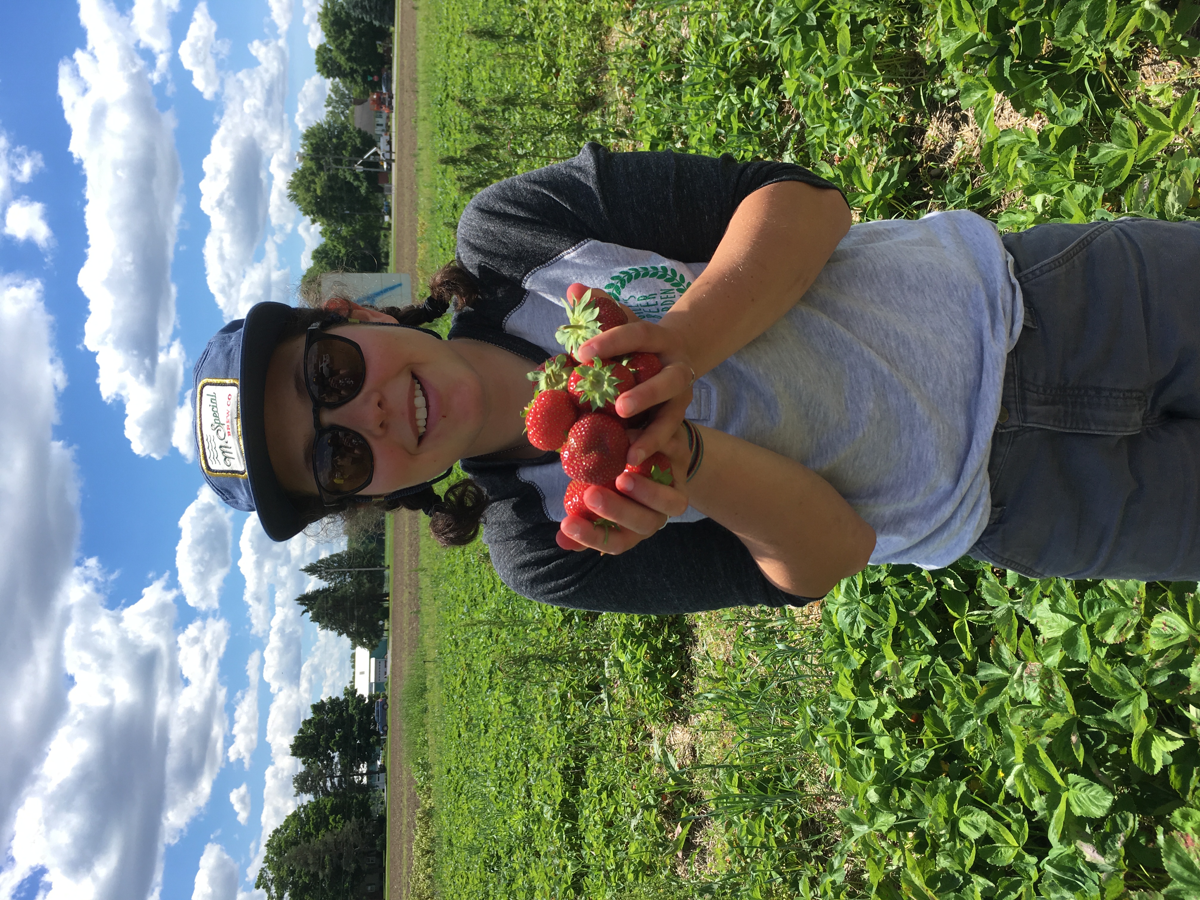 Sarah holding strawberries in a strawberry field