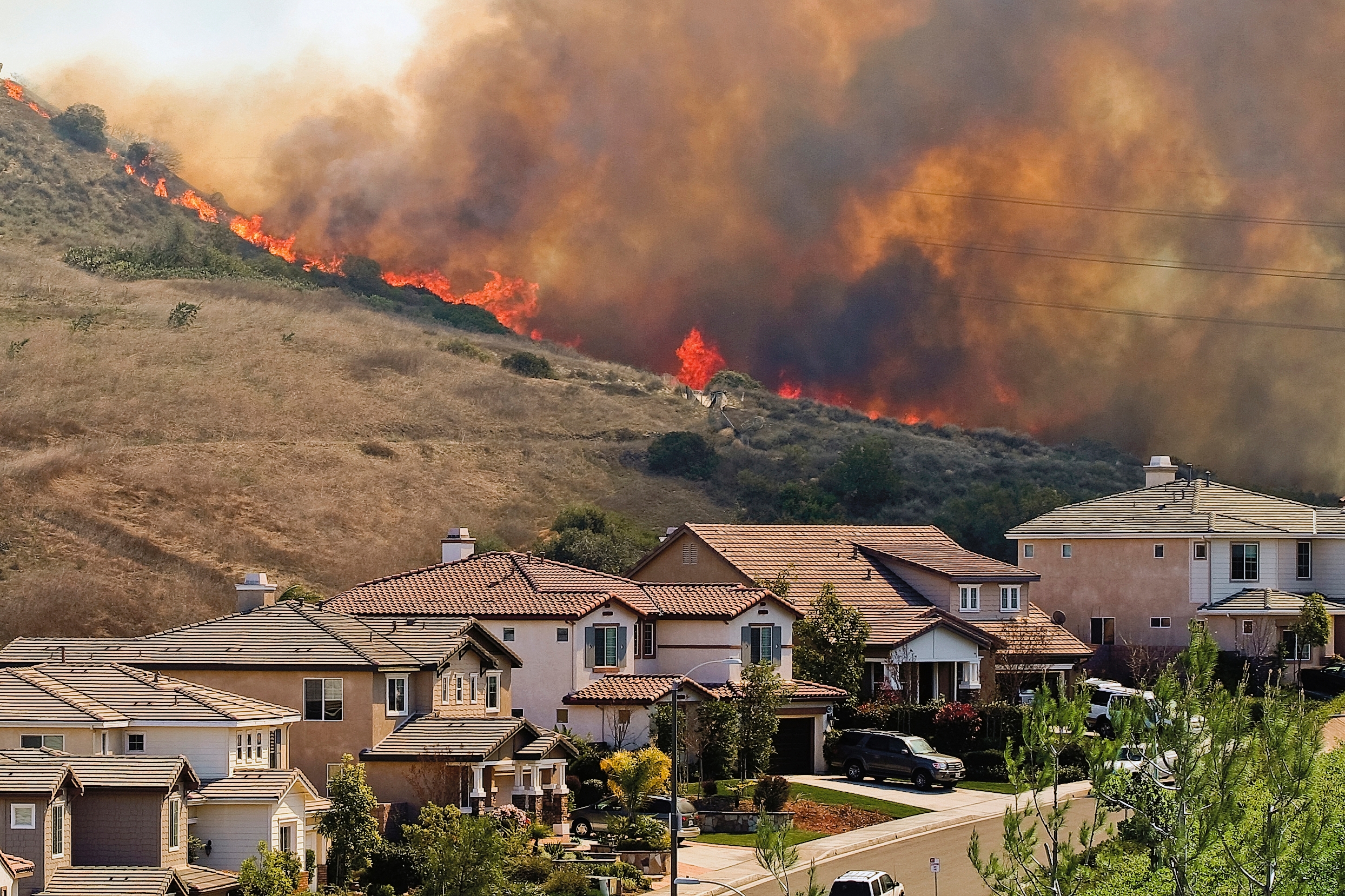 Wildfires on a hill with homes in the foreground