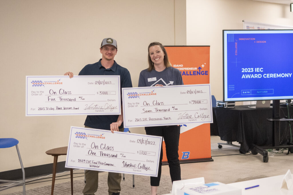 Zach Adams, Founder of On Glass, holding award checks and posing for a picture with Cara Van Sant, Venture College Director