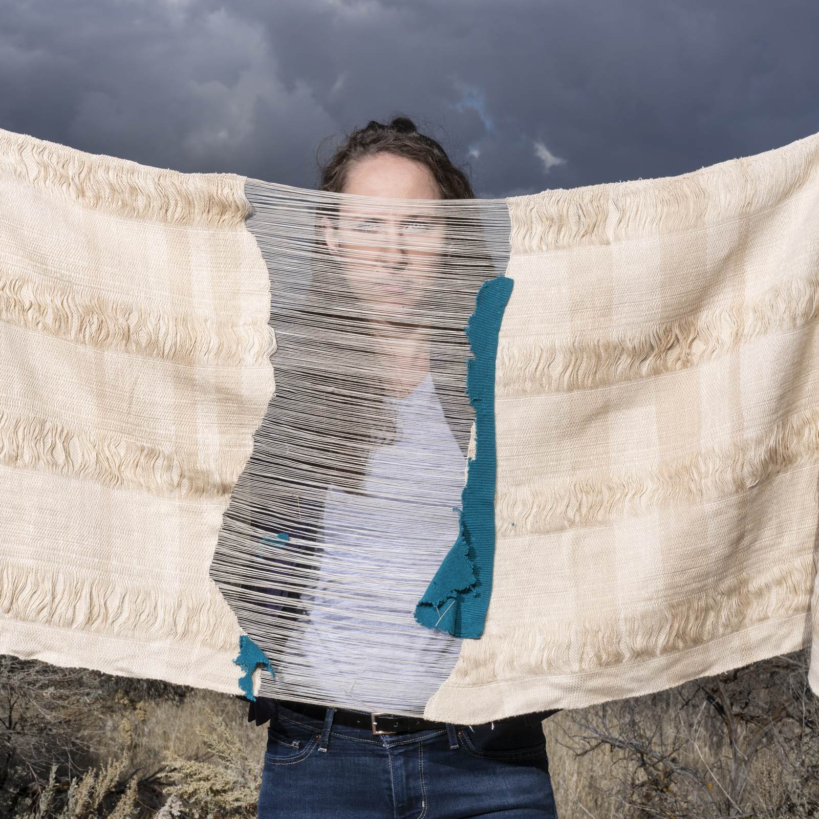 Artist Lily Lee holding burial shroud in front of her face