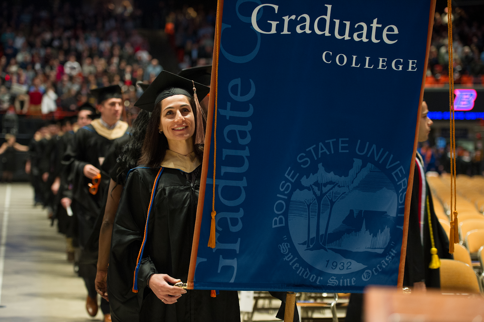 Karolin Marakool carries the Graduate college banner at Graduation