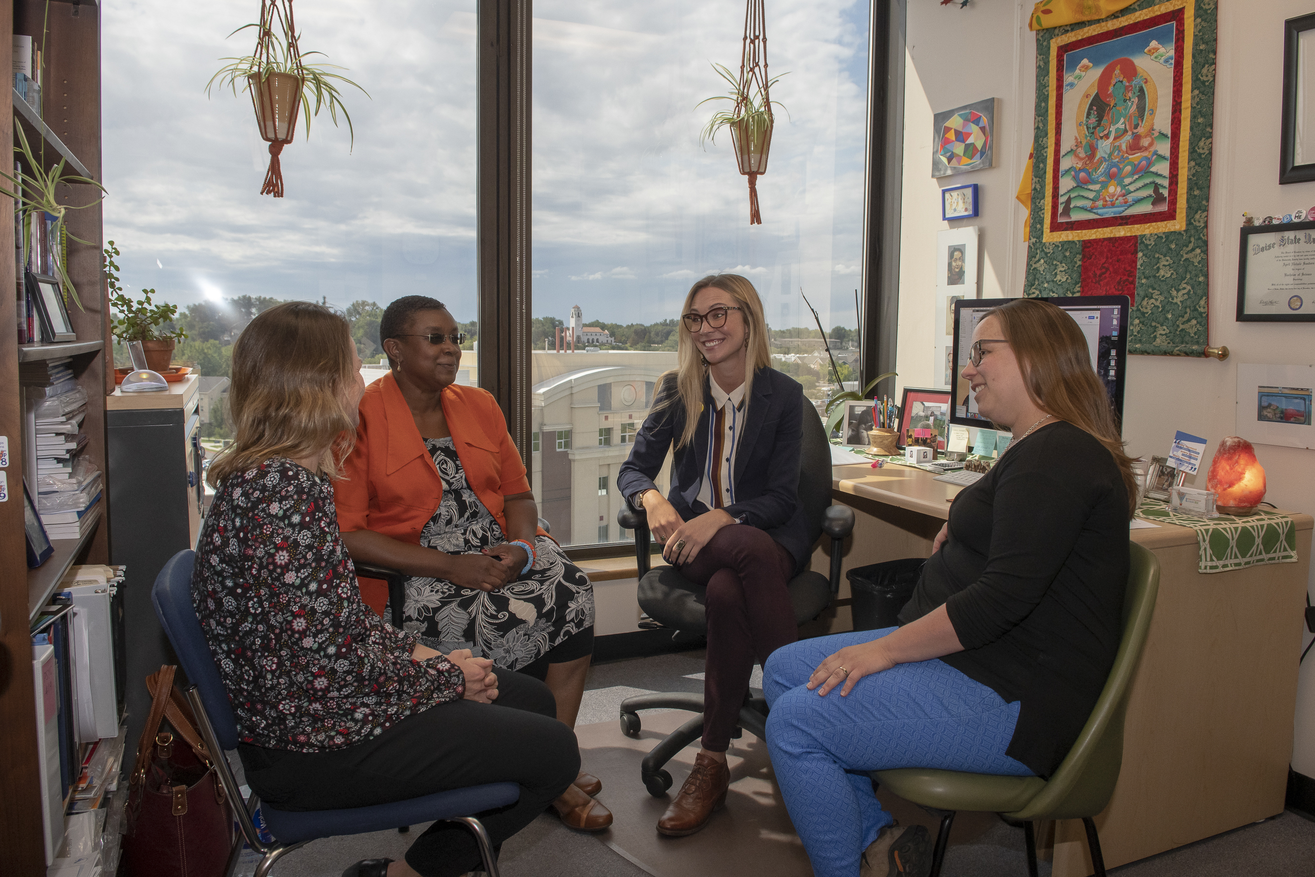 Four women converse together in office