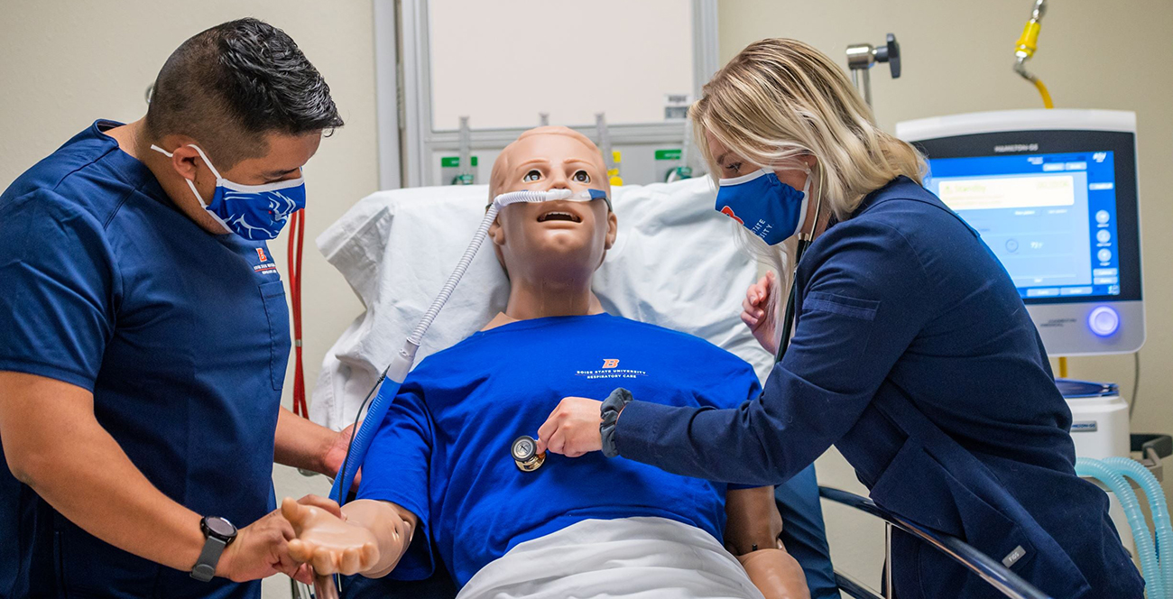 Two respiratory care students assess a manikin's vital signs