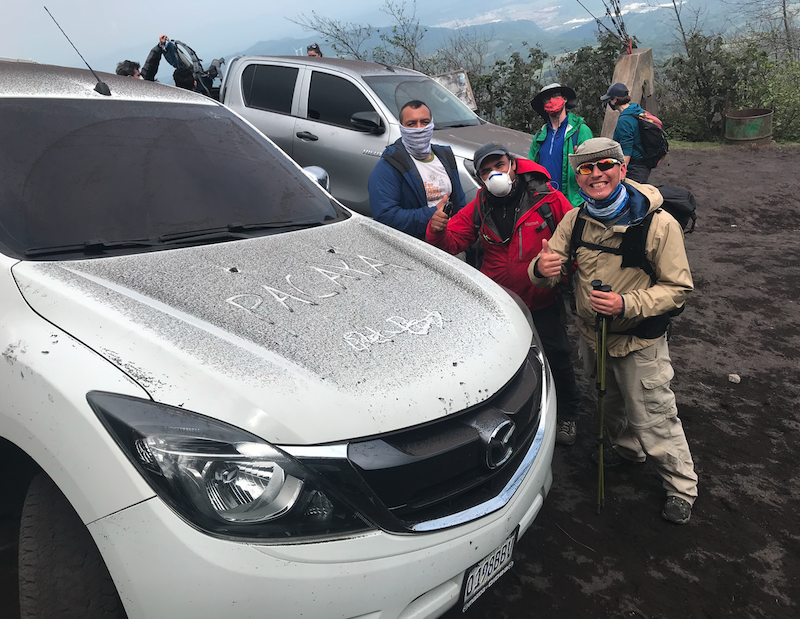 researchers stand beside car dusted with volcanic ash in Guatemala