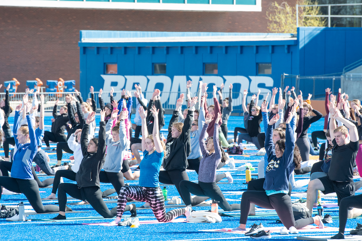 People do yoga on the boise state turf