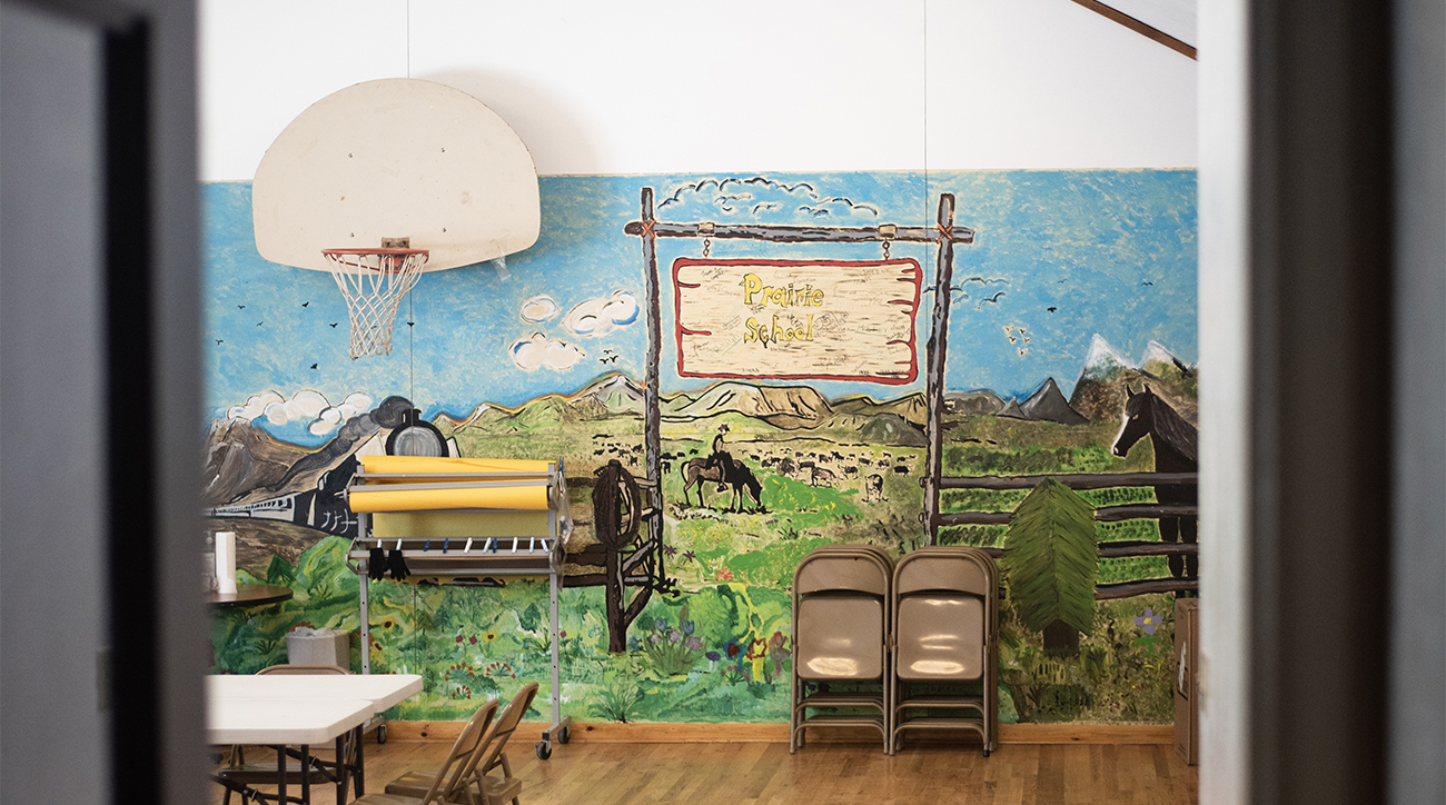 Prairie's school gymnasium with an old west mural with mountains and a person on a horse
