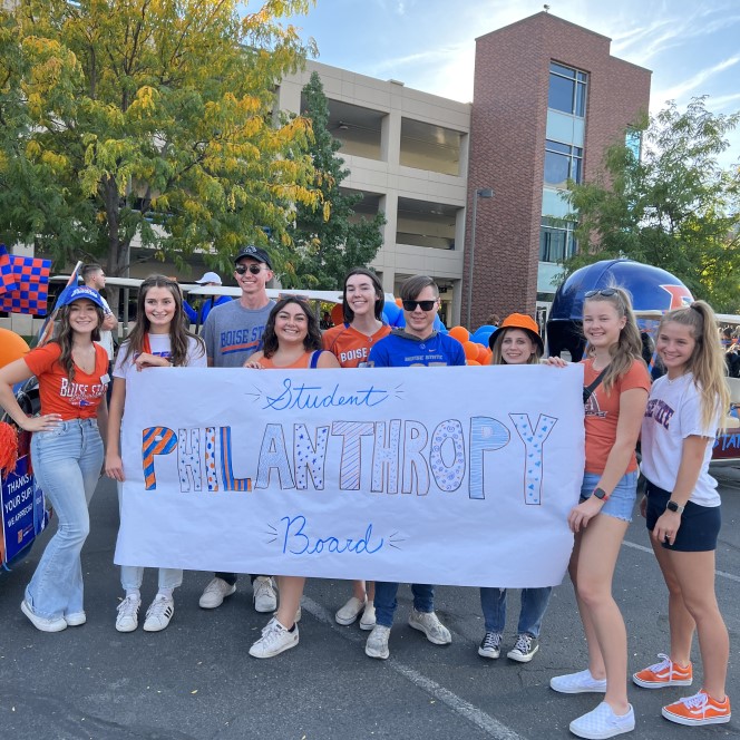 Student philanthropy board members holding a banner at homecoming