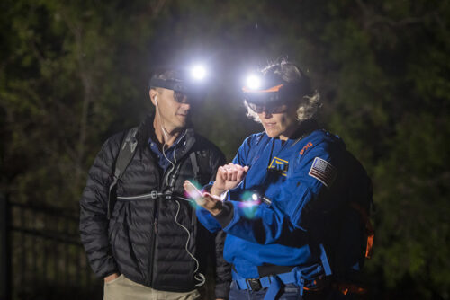 two astronauts wearing headlamps stand outside in the dark testing augmented reality displays