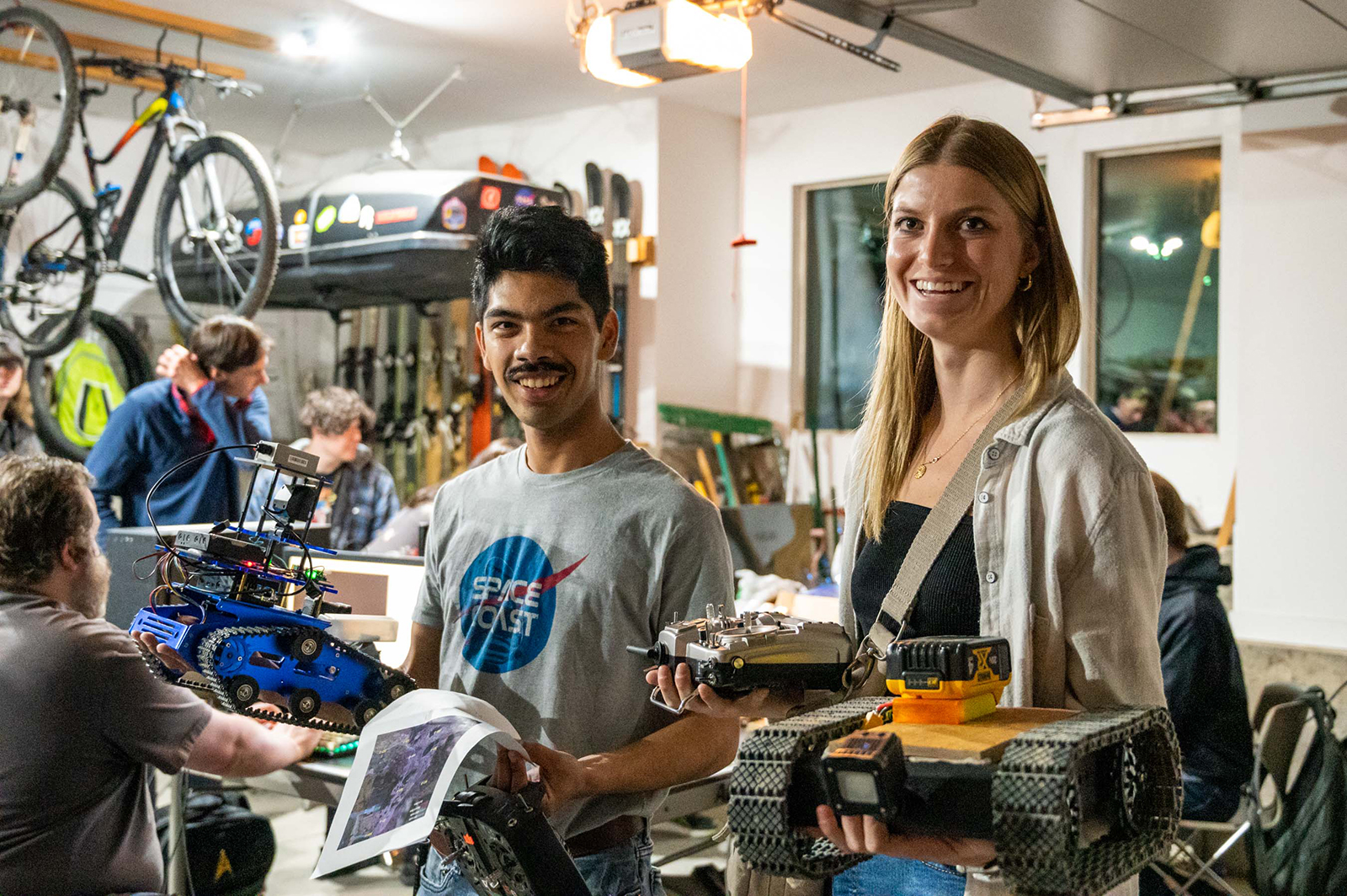 Two students smiling and holding mini rovers