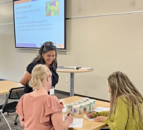 An instructor works with teachers at a table in the classroom at the Math Teaching Conference