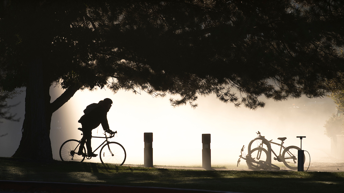 A cyclist rides against a foggy background on Boise State campus