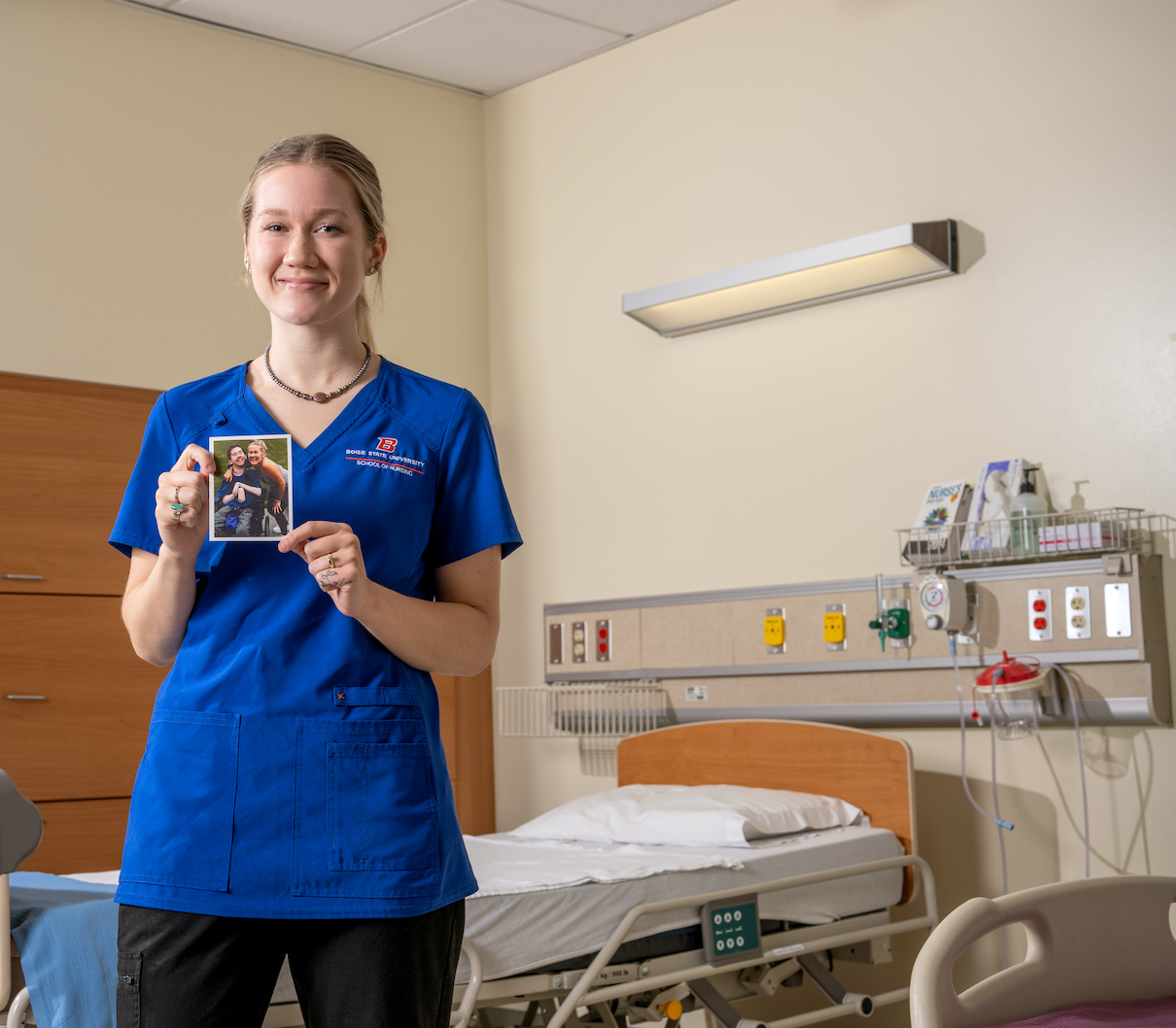 woman stands in hospital holding a photo of herself and her brother