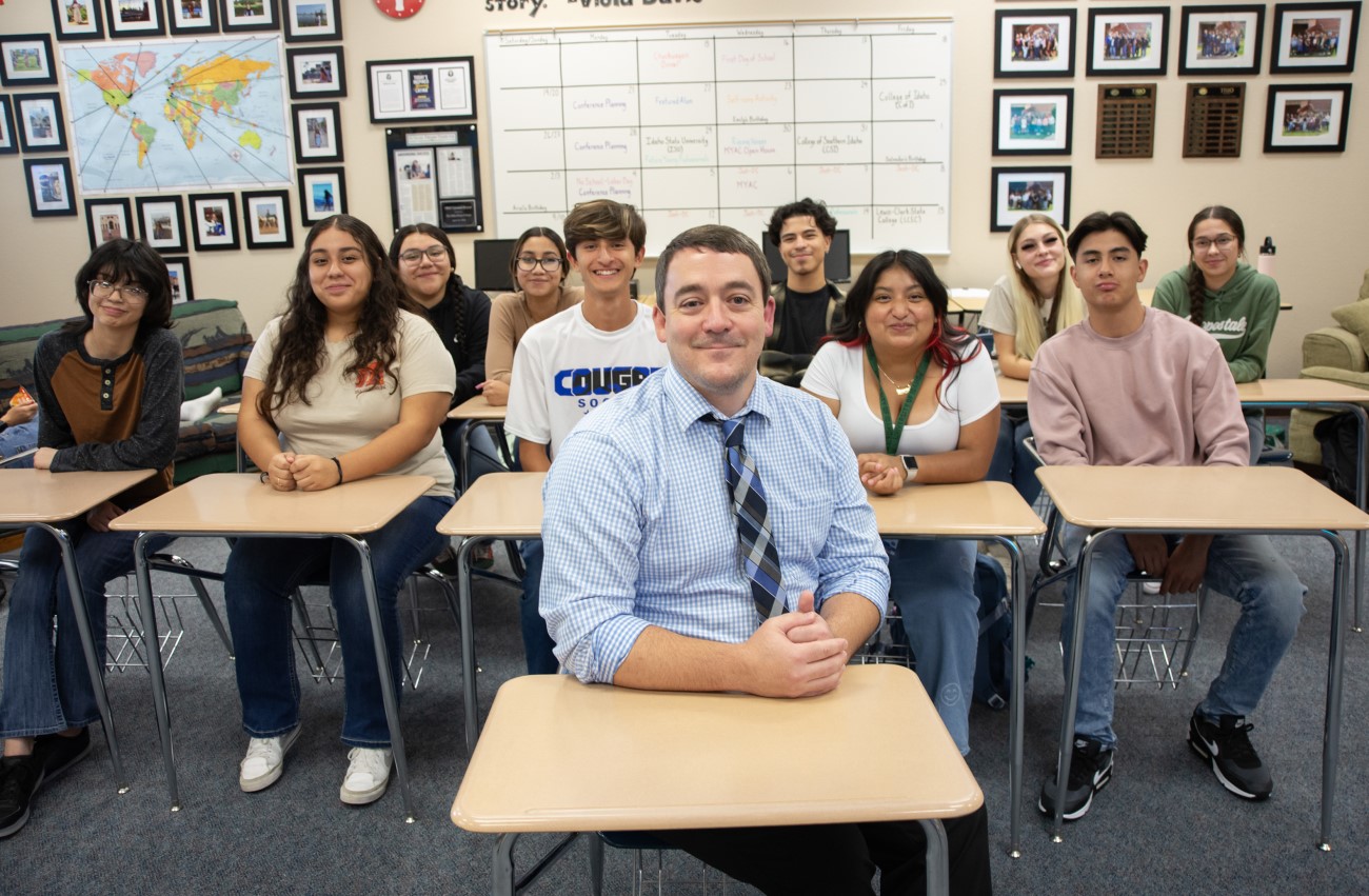 Josh Engler posing in classroom with students behind him.