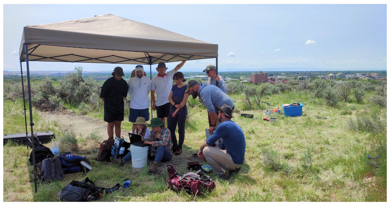 Undergraduate students are setting up geophysical testing instruments to characterize the Boise Geothermal System during a field camp led by Niu. Boise is in the background.