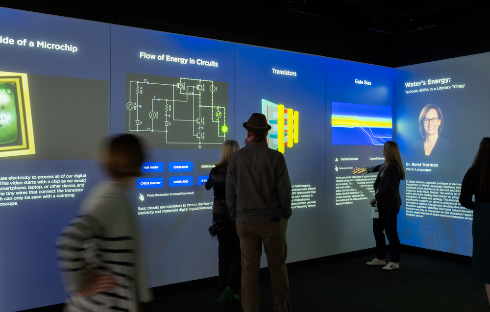 5 people view exhibits on energy flow through a circuit