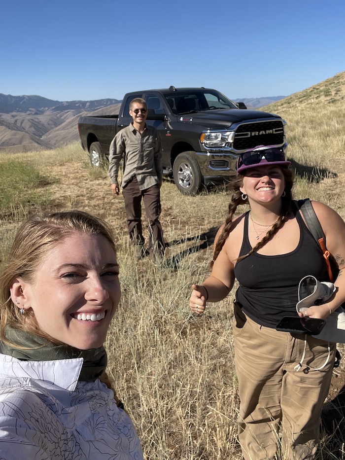 three students in rangeland by black truck