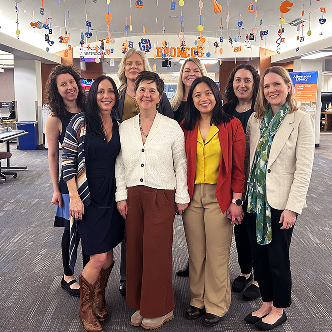 Eight Doctor of Nursing Practice students pose together in the lobby of Albertsons Library.