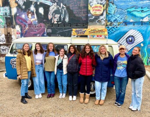 Members of the student-run Blue House Agency posing in front of a Volkswagen bus.