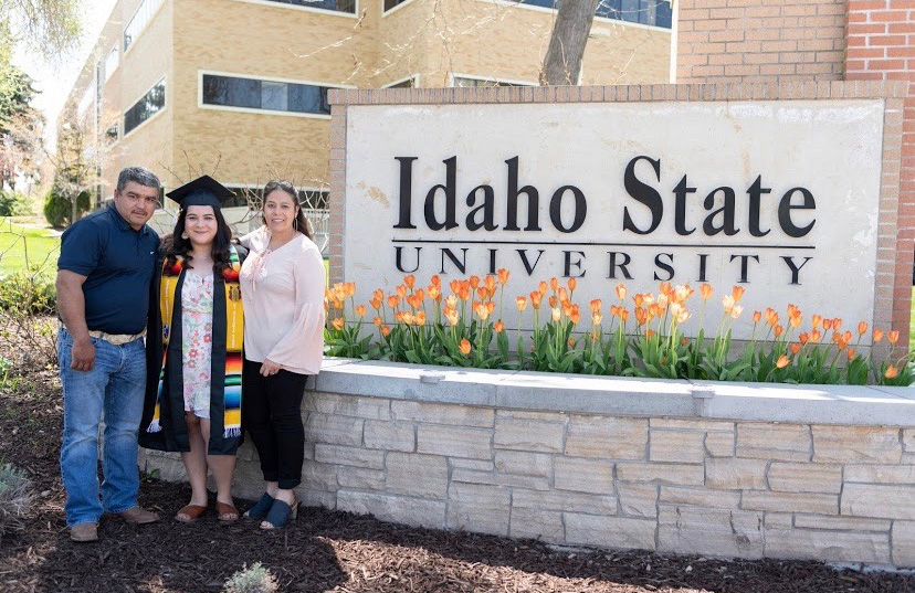 Maria Garcia De la Cruz stands with her parents by Idaho State University's sign.