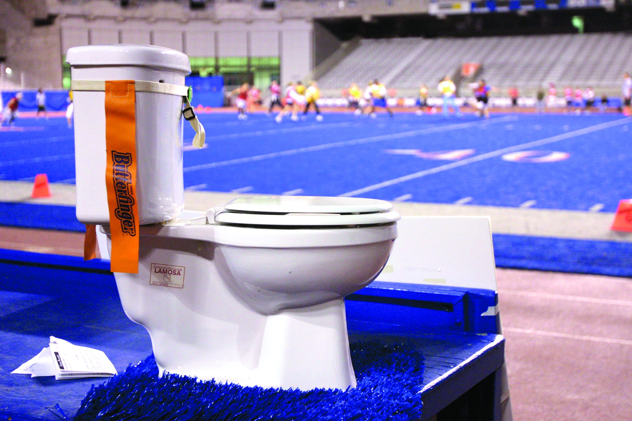A toilet with flag football flags strapped around it