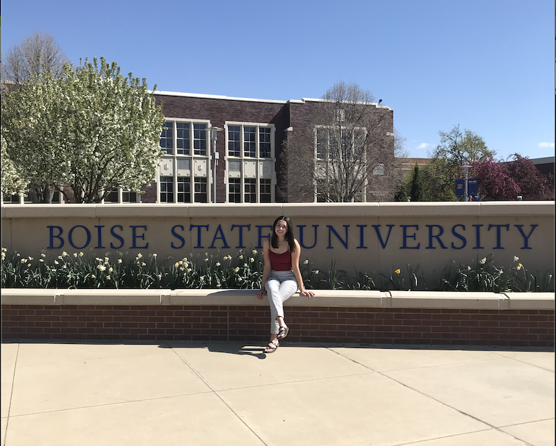Student sitting in front of boise State University sign