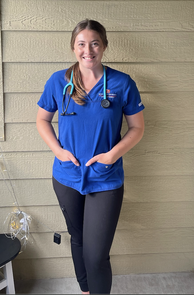 Maddy wearing nurses scrubs, a stethoscope is around her neck