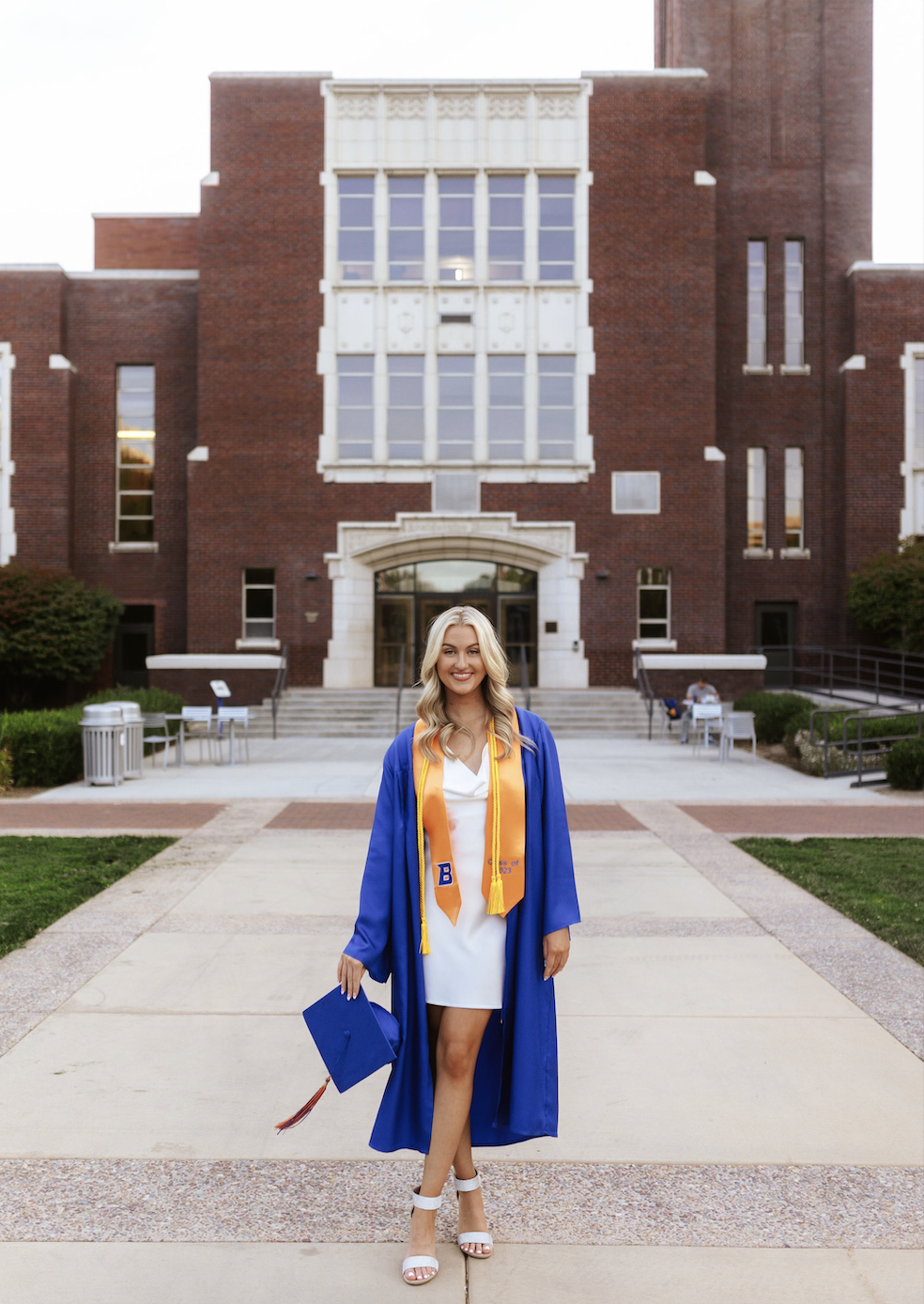 Kaylie Jones with cap and gown posing on campus